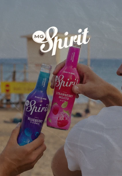 Dos personas brindando en la playa con botellas de MG Spirit Blueberry Vodka y Strawberry Mojito, diseño web de KLOROFiLA