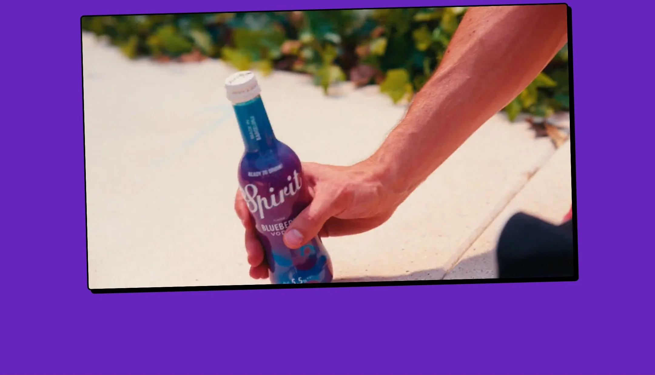 Bloque violeta con un vídeo inclinado, como una foto pegada, de una mano cogiendo una botella.
